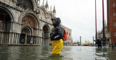 People wade their way through the water in flooded St. Mark's Square following a high tide, in Venice, Italy, Dec. 8, 2020. (AP Photo)