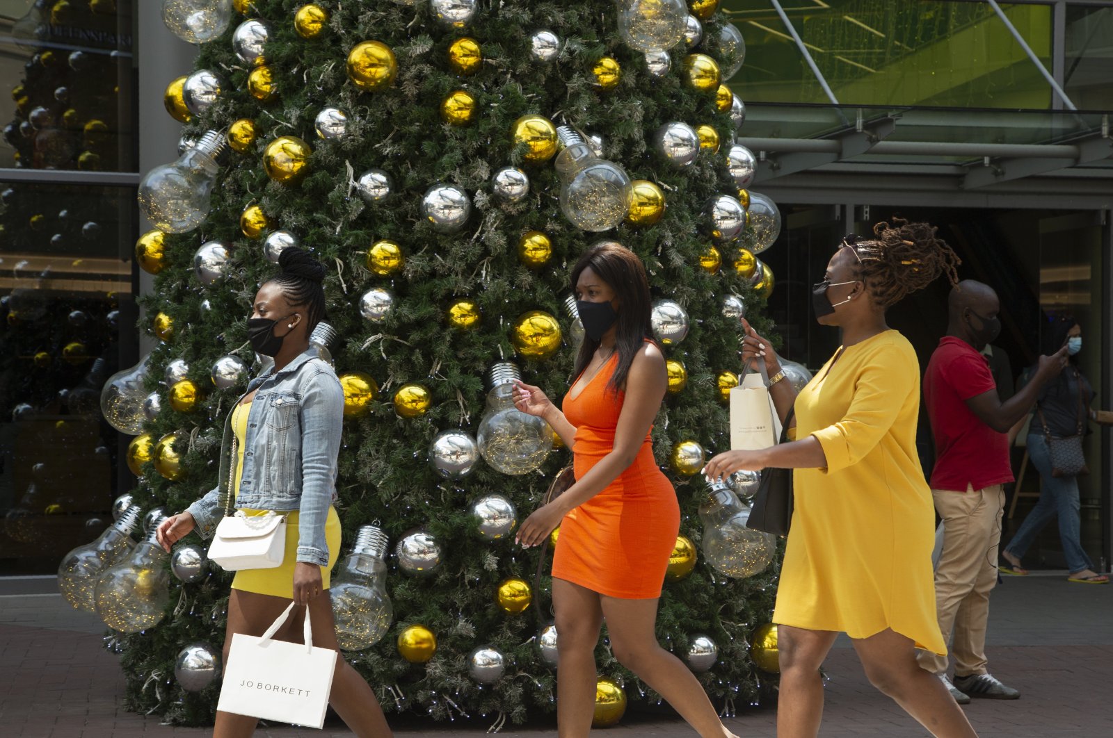 Women wearing face masks as protection against COVID-19 pass a Christmas tree at a shopping mall in Johannesburg, South Africa, Dec. 7, 2020. (AP Photo)