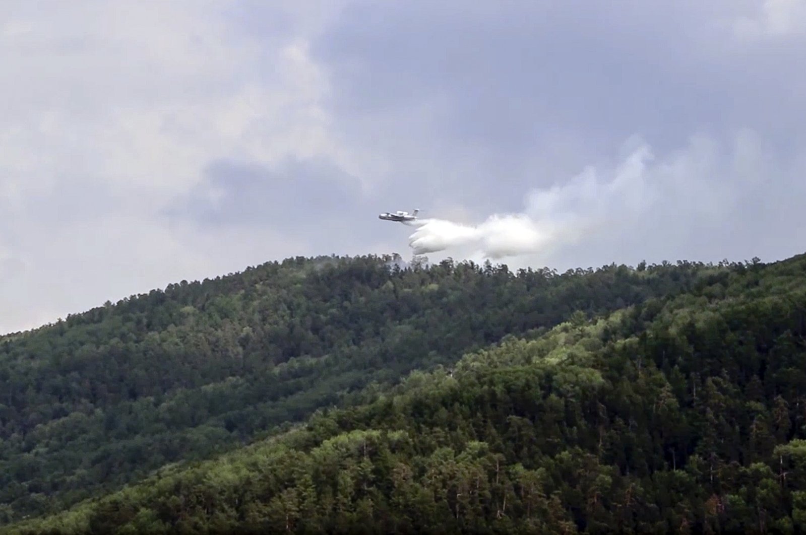 In this file image taken from a video provided by the Russian Emergency Ministry, a multipurpose amphibious aircraft releases water to extinguish a fire in the Trans-Baikal National Park in Buryatia, southern Siberia, Russia on July 10, 2020. (AP Photo)