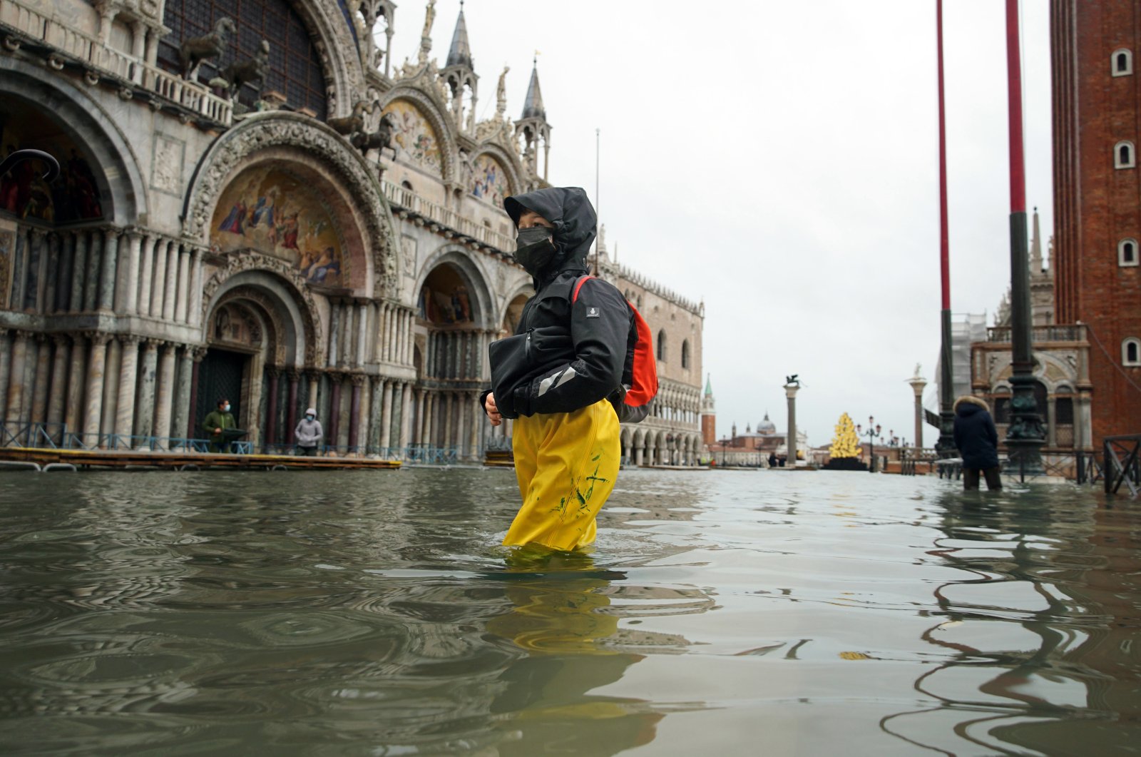 People wade their way through the water in flooded St. Mark's Square following a high tide, in Venice, Italy, Dec. 8, 2020. (AP Photo)