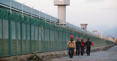 Workers walk by the perimeter fence of what is officially known as a vocational skills education center in Dabancheng, Xinjiang Uighur Autonomous Region, China, Sept. 4, 2018. (Reuters Photo)