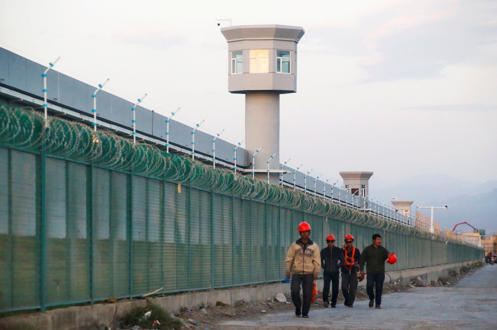Workers walk by the perimeter fence of what is officially known as a vocational skills education center in Dabancheng, Xinjiang Uighur Autonomous Region, China, Sept. 4, 2018. (Reuters Photo)