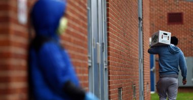 People carry food donated by volunteers from the Baltimore Hunger Project outside of Padonia International Elementary school in Cockeysville, Maryland, U.S., Dec. 4, 2020. (AFP Photo)
