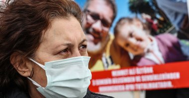 Emine Öztürk stands in front of a picture of her husband Mehmet Ali, imprisoned in the UAE, alongside their daughter, in Istanbul, Dec.11, 2020. (AA Photo)