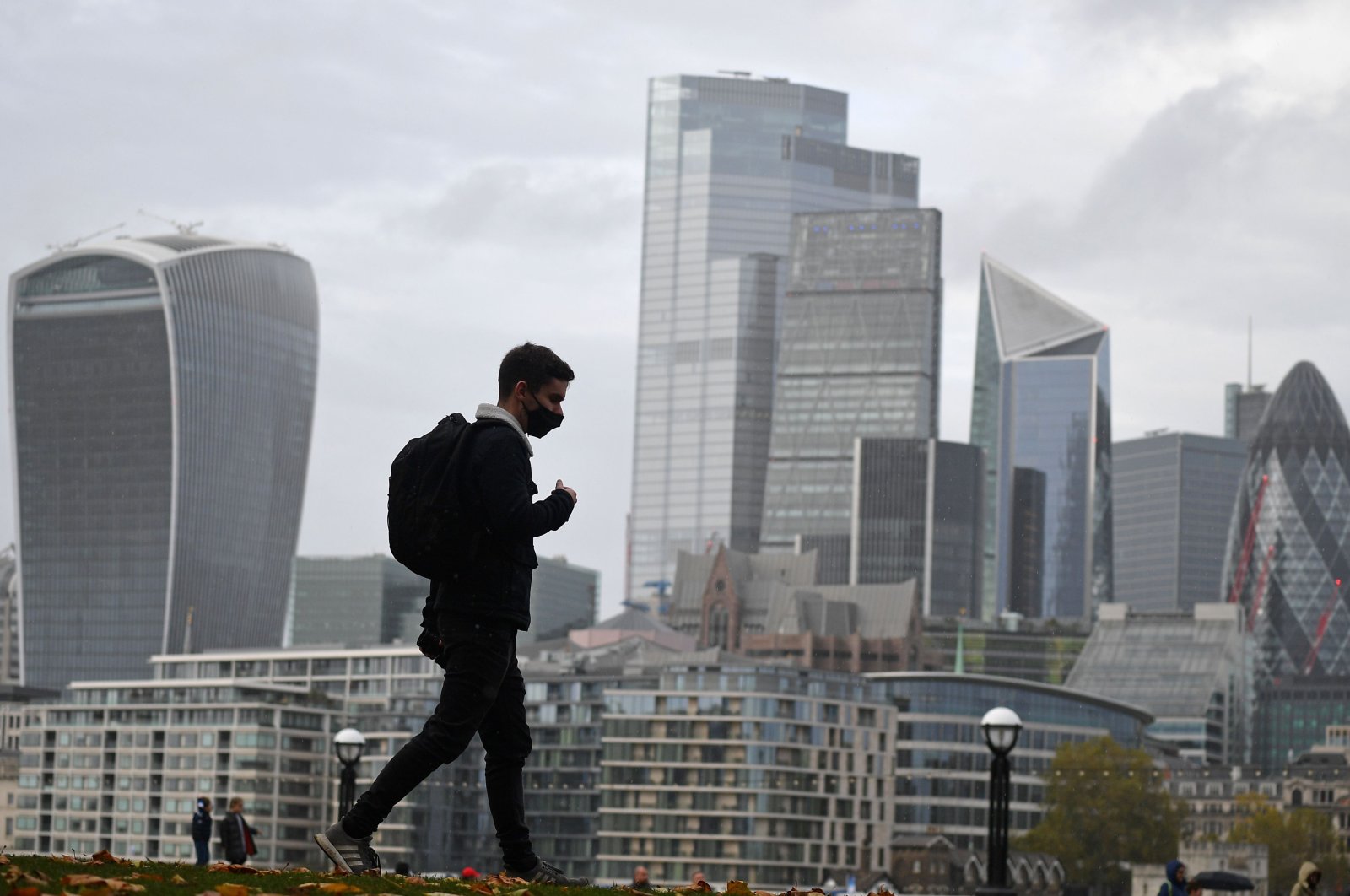 A man walks along the southern bank of the River Thames with the office towers of the City of London on Nov. 1, 2020. (AFP Photo)
