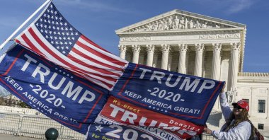 Kathy Kratt of Orlando, Florida, displays her Trump flags as she and other protesters demonstrate their support for President Donald Trump at the U.S. Supreme Court in Washington, Dec. 11, 2020. (AP Photo)
