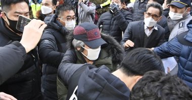 Cho Doo-soon (C), escorted by police officers, arrives home in Ansan, South Korea, Dec. 12, 2020. (AP Photo)
