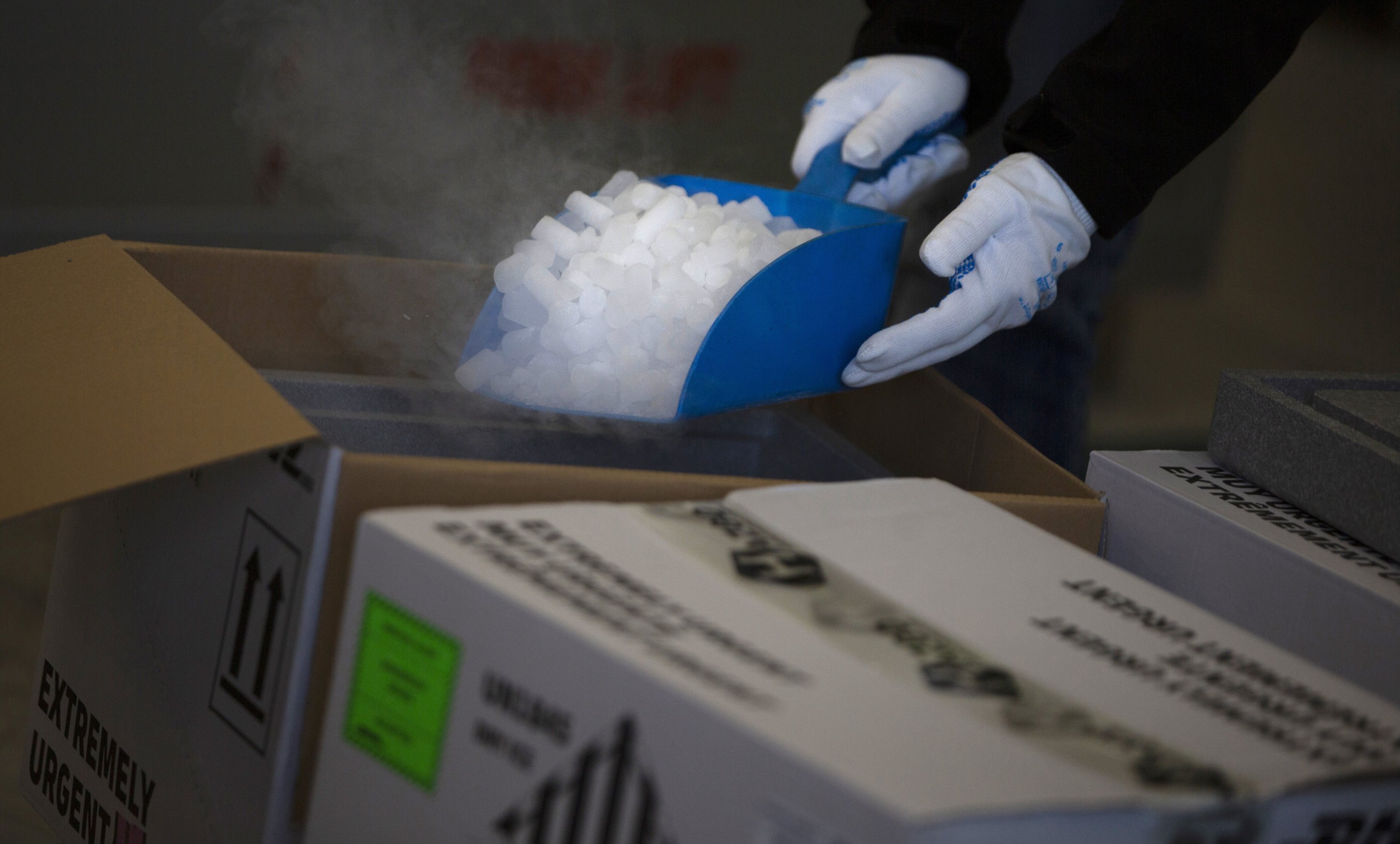 A worker shows how dry ice is used on specific vaccines and medicines to keep them cool during a demonstration at a cargo warehouse in Steenokkerzeel, Belgium, Dec. 1, 2020. (AP Photo)