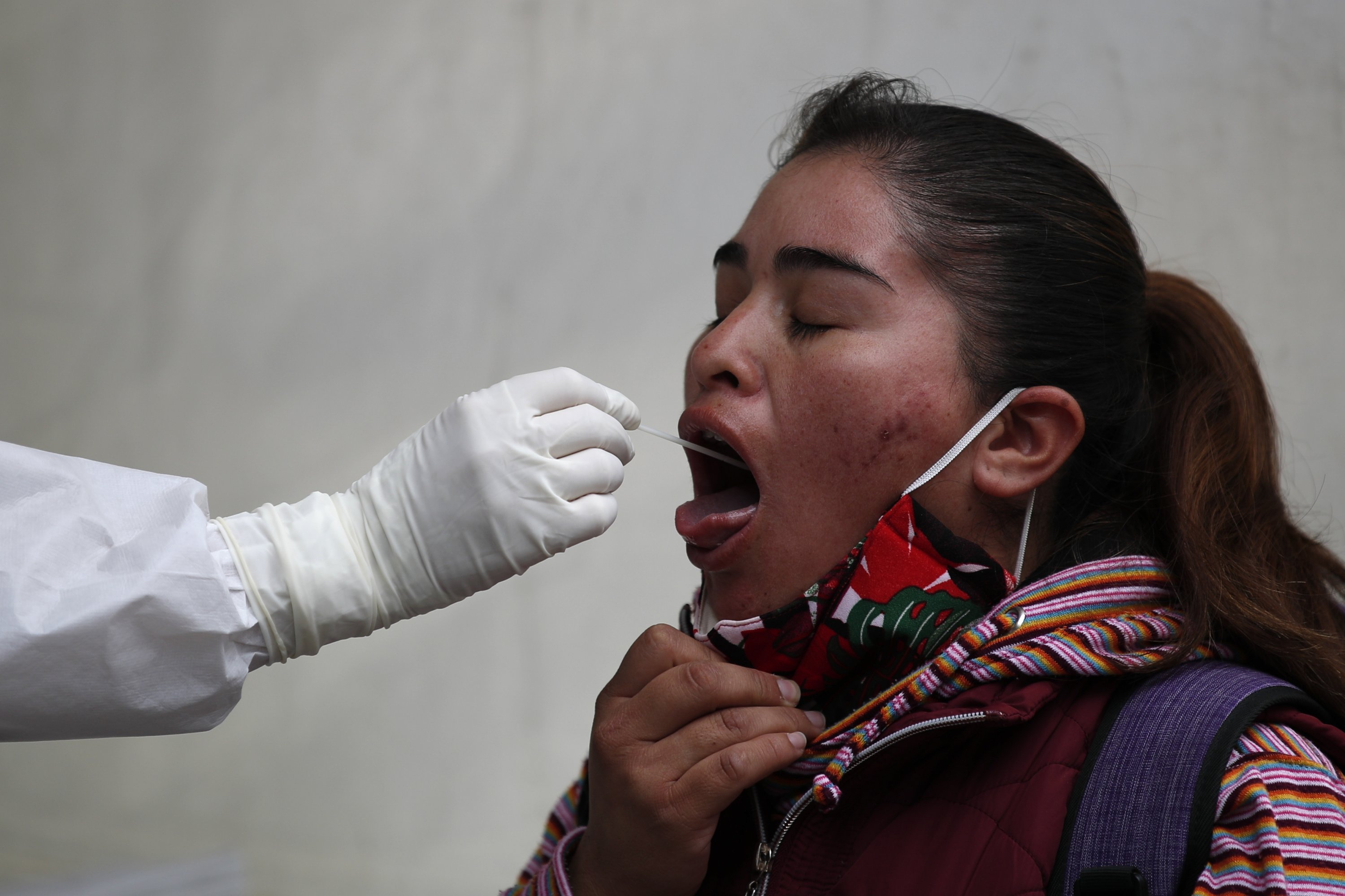 A doctor collects a throat swab for a COVID-19 test at a post set up by the city department of health to perform mainly rapid tests, outside the Pino Suarez subway station in central Mexico City, Dec. 4, 2020. (AP Photo)