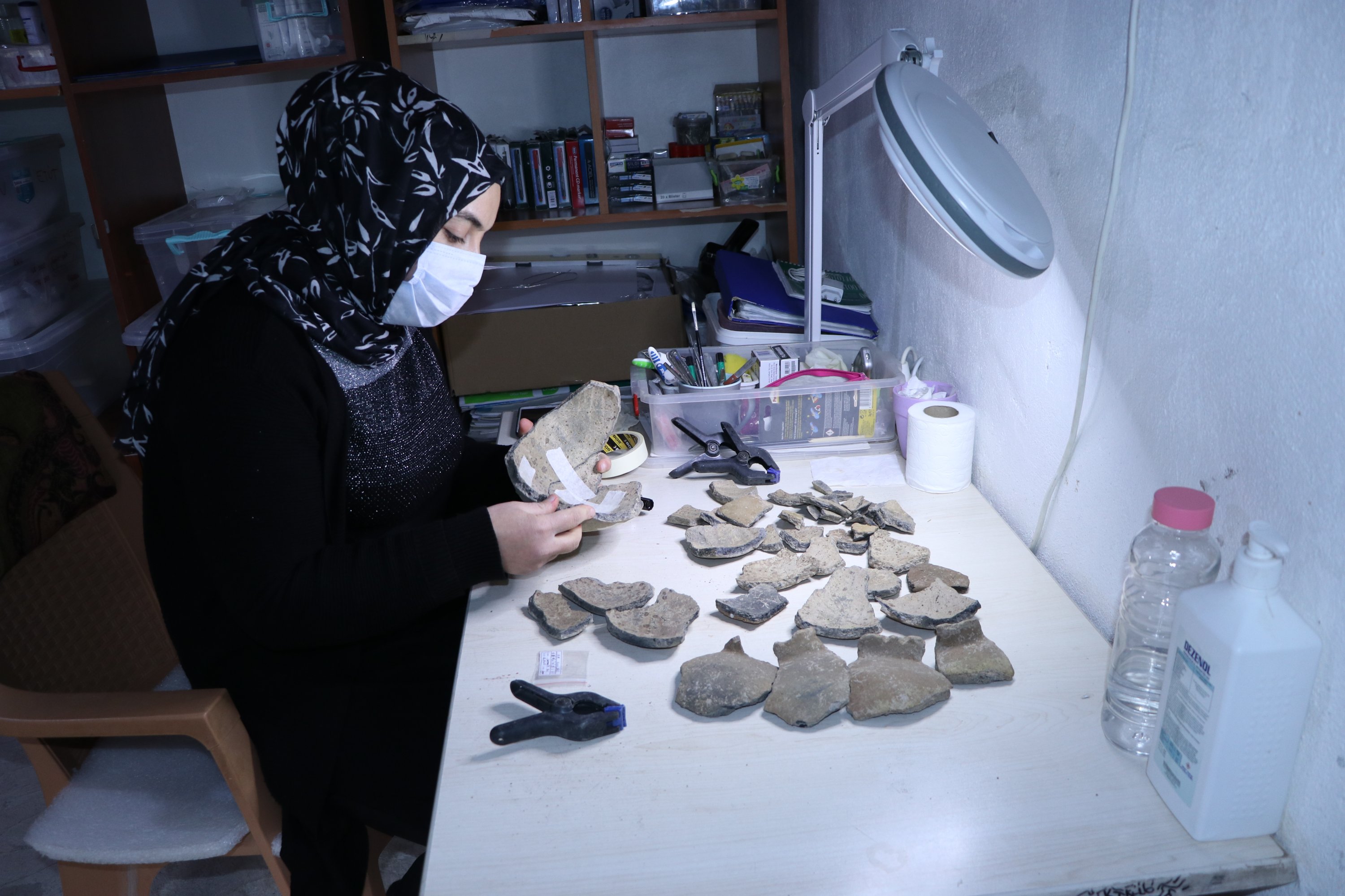 An archaeologist works on artifacts found at the mounds of Ambar, Kendale Hecala and Gre Fılla in Diyarbakır, eastern Turkey, Dec. 12, 2020. (AA PHOTO)