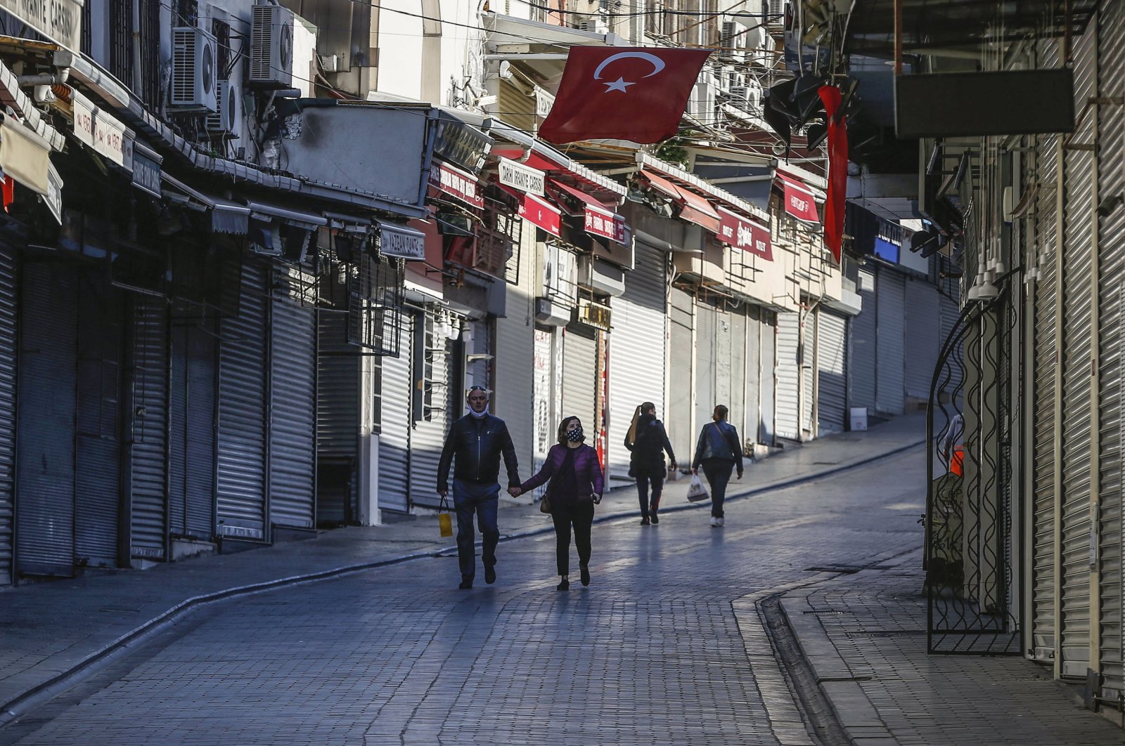 People wearing masks as a preventive measure against the spread of coronavirus, walk by closed shops at Eminönü Bazaar in  just hours before the start of a two-day curfew, Istanbul, Turkey, April 17, 2020. (AP Photo)