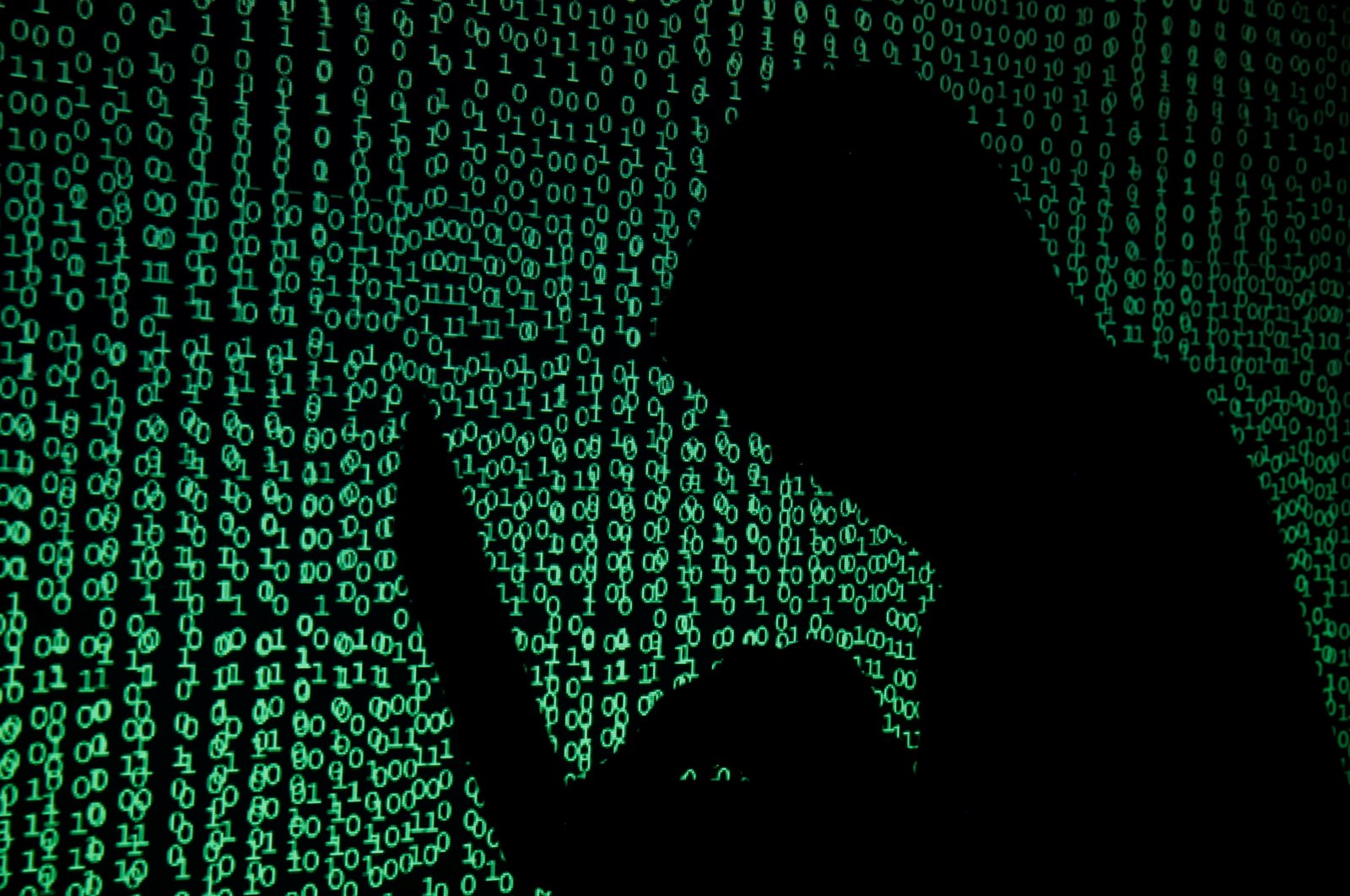 A hooded man holds a laptop computer as cyber code is projected on him in this illustration picture taken on May 13, 2017. (Reuters Photo)