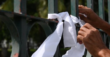 A man ties a white ribbon on a fence at a cemetery as a sign of protest against the government policy of forced cremations of Muslims who die of the coronavirus, in Colombo, Sri Lanka, Dec. 14, 2020. (AFP Photo)