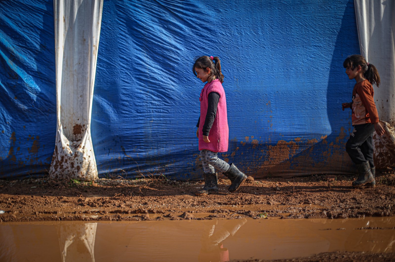 Two girls walk past a tent for people displaced by the Bashar Assad regime in northwestern Idlib province, Syria, Dec. 12, 2020. (AA Photo)