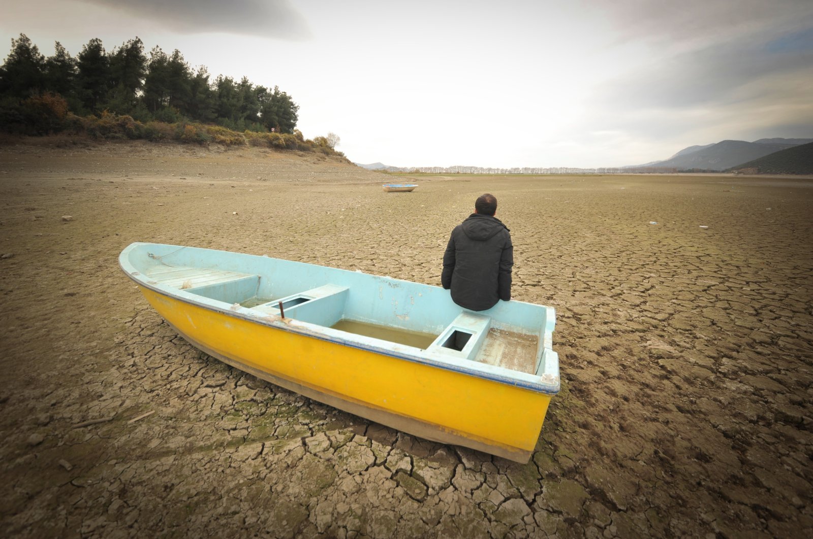 A man sits on a small boat on a dried part of Gölbaşı Dam in the Kestel district, in Bursa, northwestern Turkey, Dec. 11, 2020. (DHA PHOTO) 