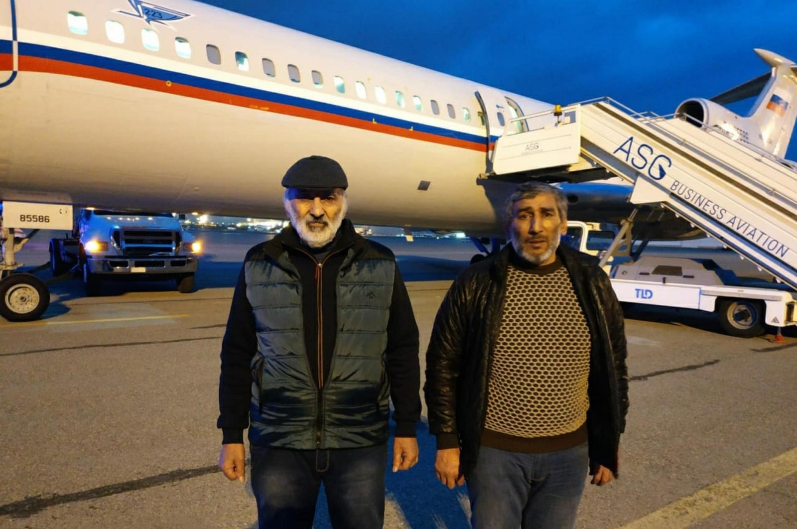 Dilgam Asgarov (L) and Shahbaz Guliyev, who had been held captive by Armenia for six years, stand in front of a plane after being released and brought to Baku, Azerbaijan, Dec.14, 2020. (AA)