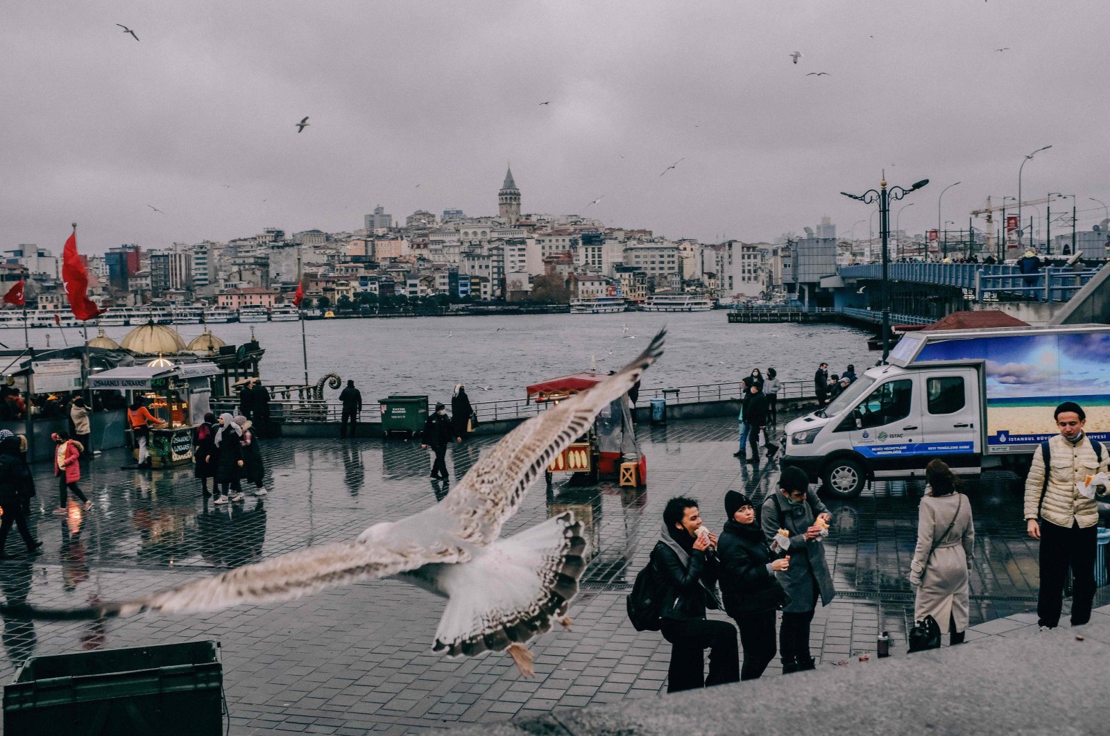 Birds fly as bystanders eat at Eminönü Square in Istanbul, Turkey, Dec. 15, 2020. (AFP Photo)