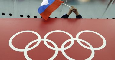 A Russian flag is held above the Olympic Rings at Adler Arena Skating Center during the Winter Olympics in Sochi, Russia on Feb. 18, 2014. (AP Photo)