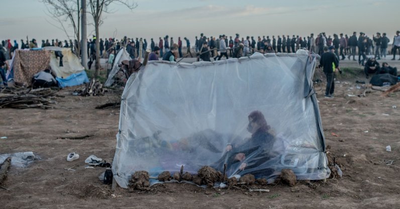 A Syrian woman sits in a tent with her son as others wait for food distribution in front of the Pazarkule border crossing to Greece, in Edirne, Turkey, March 3, 2020. (AFP Photo)