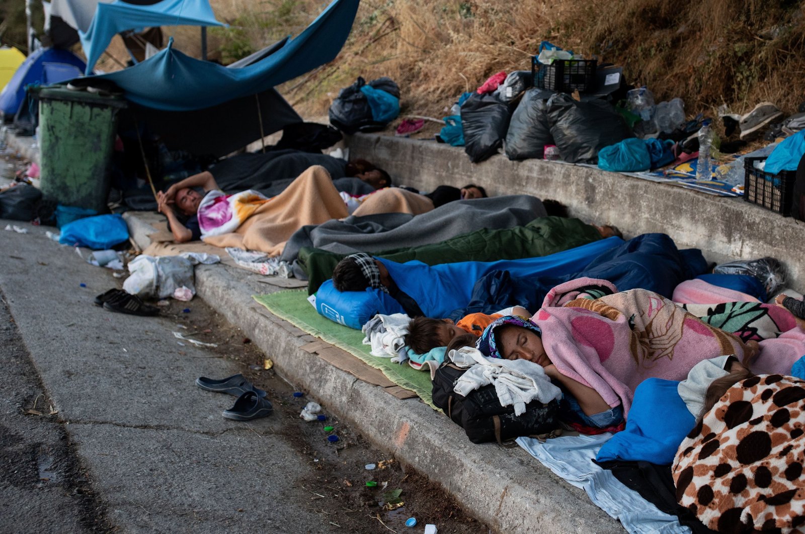 Refugees and migrants from the destroyed Moria camp sleep on the side of a road, on the island of Lesbos, Greece, Sep.13, 2020. (Reuters Photo)