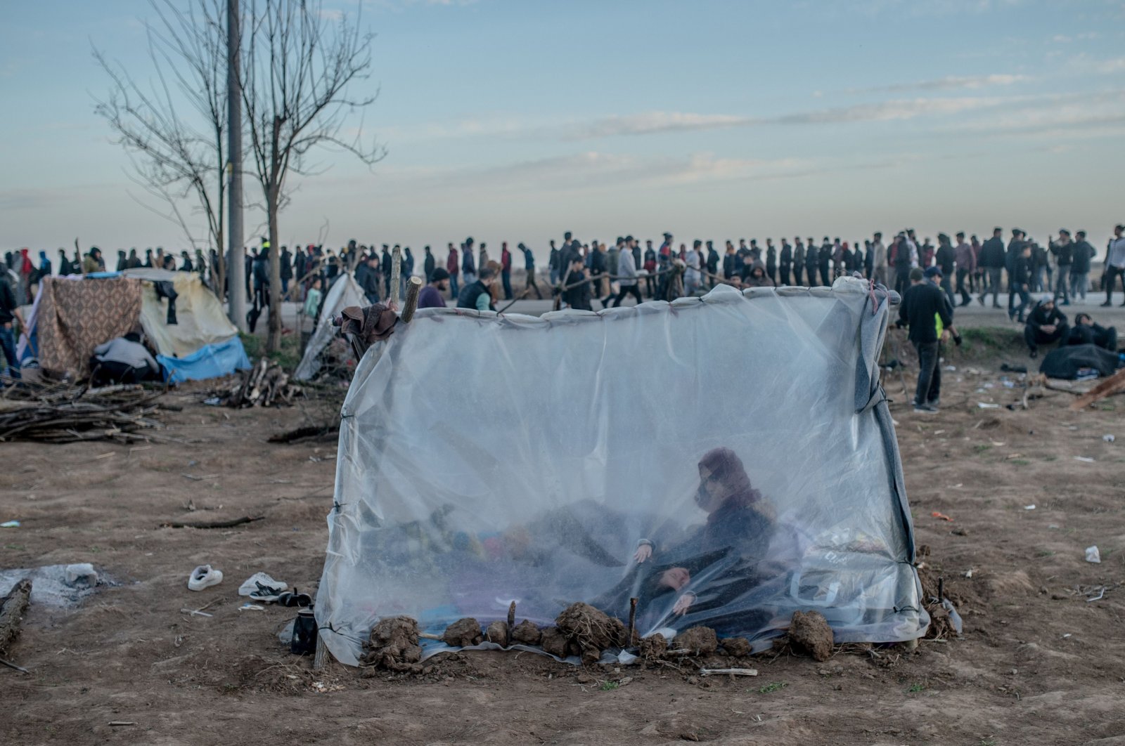 A Syrian woman sits in a tent with her son as others wait for food distribution in front of the Pazarkule border crossing to Greece, in Edirne, Turkey, March 3, 2020. (AFP Photo)