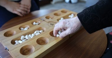 Two people play the traditional Turkish strategy and intelligence game Mangala.