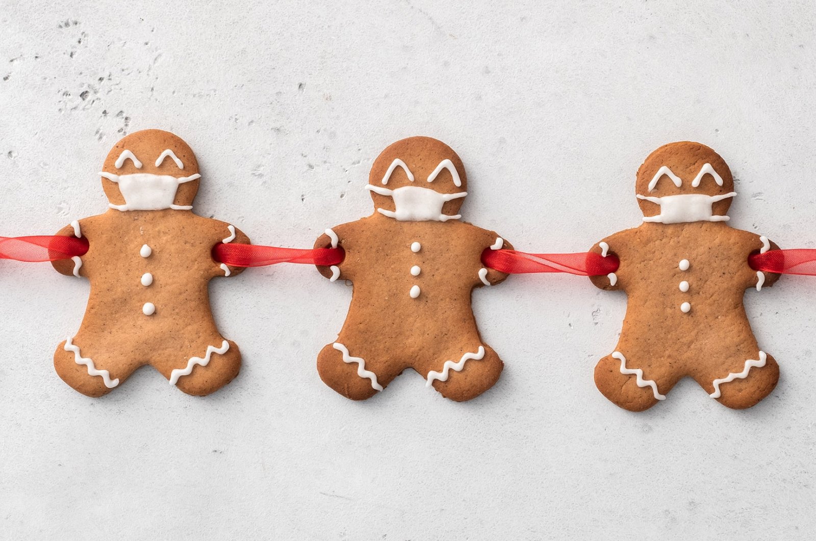 Cut out holes in your gingerbread men's hands before cooking to join them together with a ribbon and add icing masks. (Shutterstock Photo)