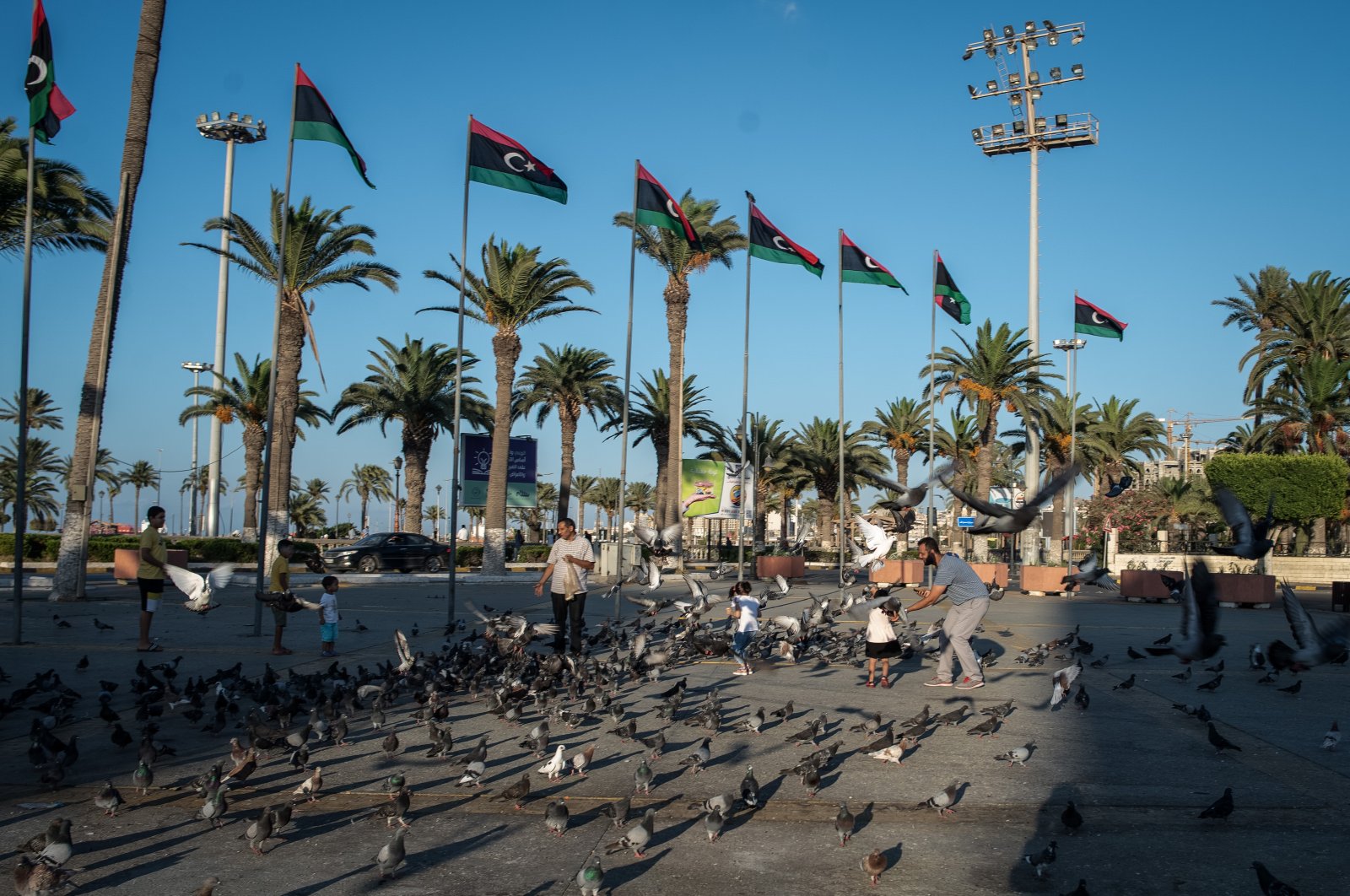 A family feeds pigeons in Martyrs' Square during a coronavirus lockdown, Tripoli, Libya, Aug. 8, 2020. (Photo by Getty Images)