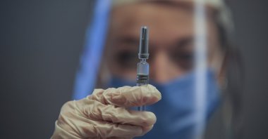 A nurse poses for the photographer as she holds a CoronaVac vaccine, made by Sinovac, currently on phase III clinical trials at Acıbadem Hospital in Istanbul, Dec. 21, 2020. (AP Photo)
