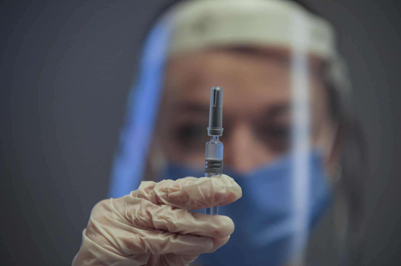 A nurse poses for the photographer as she holds a CoronaVac vaccine, made by Sinovac, currently on phase III clinical trials at Acıbadem Hospital in Istanbul, Dec. 21, 2020. (AP Photo)
