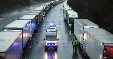Police cars pass by lorries queueing on M20 motorway to enter port Dover, as EU countries impose a travel ban from the U.K. following the coronavirus outbreak, near Ashford, Britain, Dec. 23, 2020. (Reuters Photo)