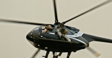 Members of U.S. private security company, Blackwater, patrol the skies of Baghdad on board a Huges 500 helicopter, April 22, 2004 (AFP Photo)
