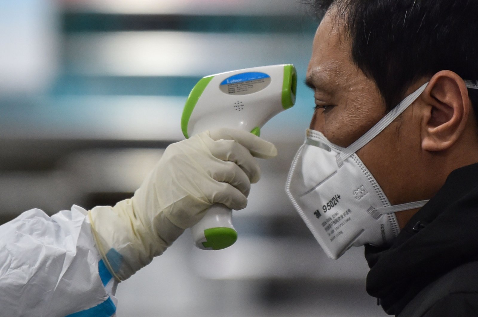A medical staff member (L) wearing protective clothing takes the temperature of a man at the Wuhan Red Cross Hospital in Wuhan, China, Jan. 25, 2020. (AFP PHOTO)