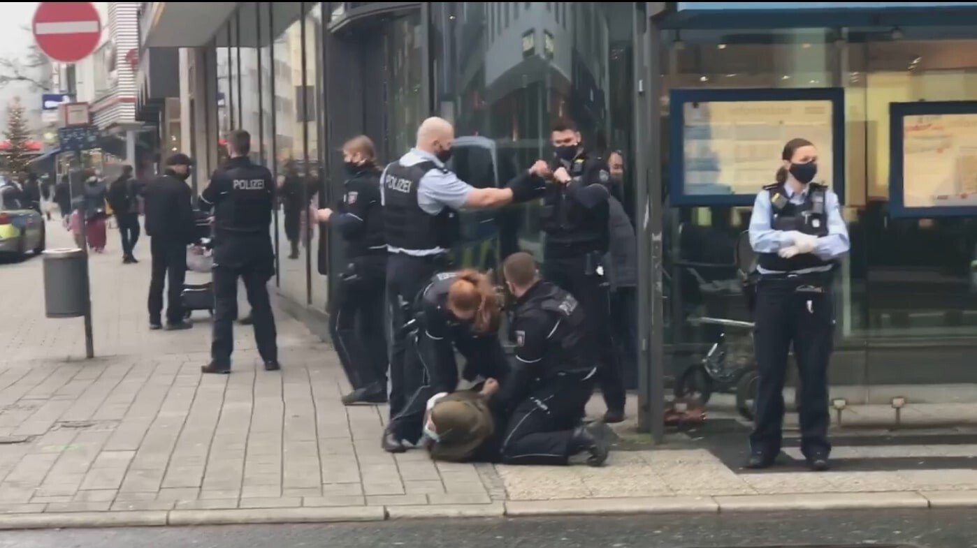 This screengrab from a footage captured by a bystander shows police officers violently arresting a Muslim woman in front of her toddler for not wearing mask in Wuppertal, Germany. (IHA Photo)