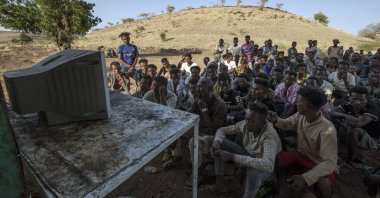Men who fled the conflict in Ethiopia's Tigray region watch the news on television, at Umm Rakouba refugee camp in Qadarif, eastern Sudan, Dec. 5, 2020. (AP Photo)