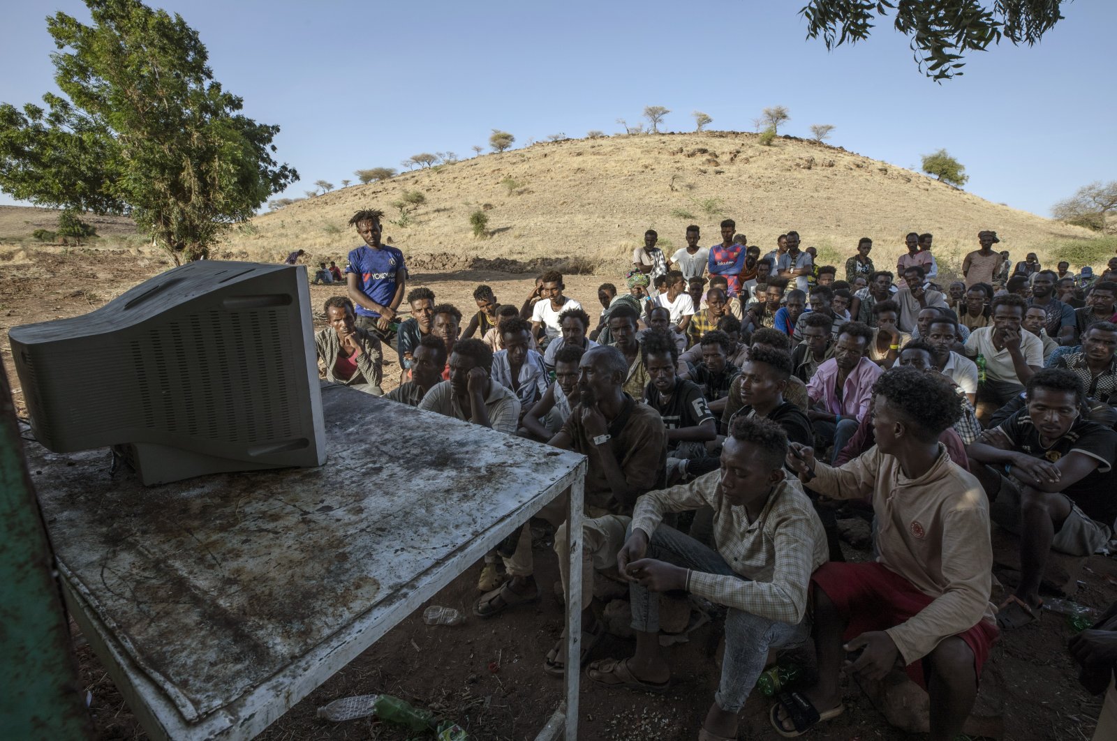 Men who fled the conflict in Ethiopia's Tigray region watch the news on television, at Umm Rakouba refugee camp in Qadarif, eastern Sudan, Dec. 5, 2020. (AP Photo)