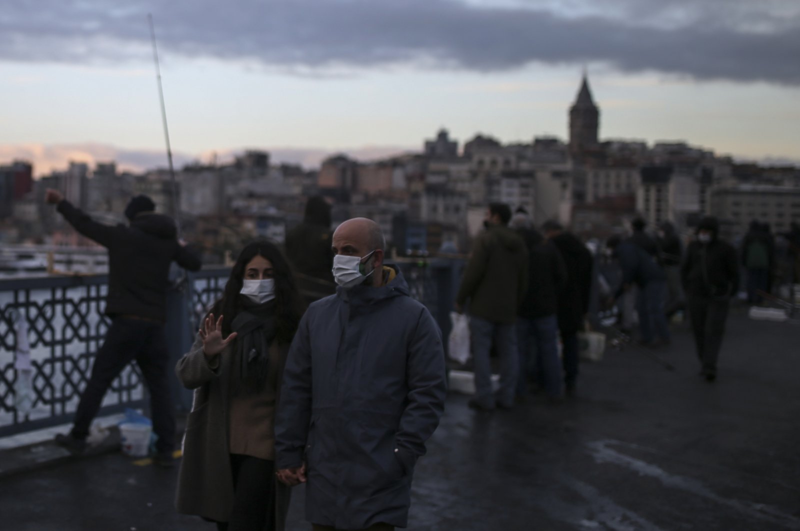 People, wearing protective masks to help curb the spread of the coronavirus, walk on the Galata Bridge over the Golden Horn in Istanbul, Monday, Dec. 21, 2020. (AP)