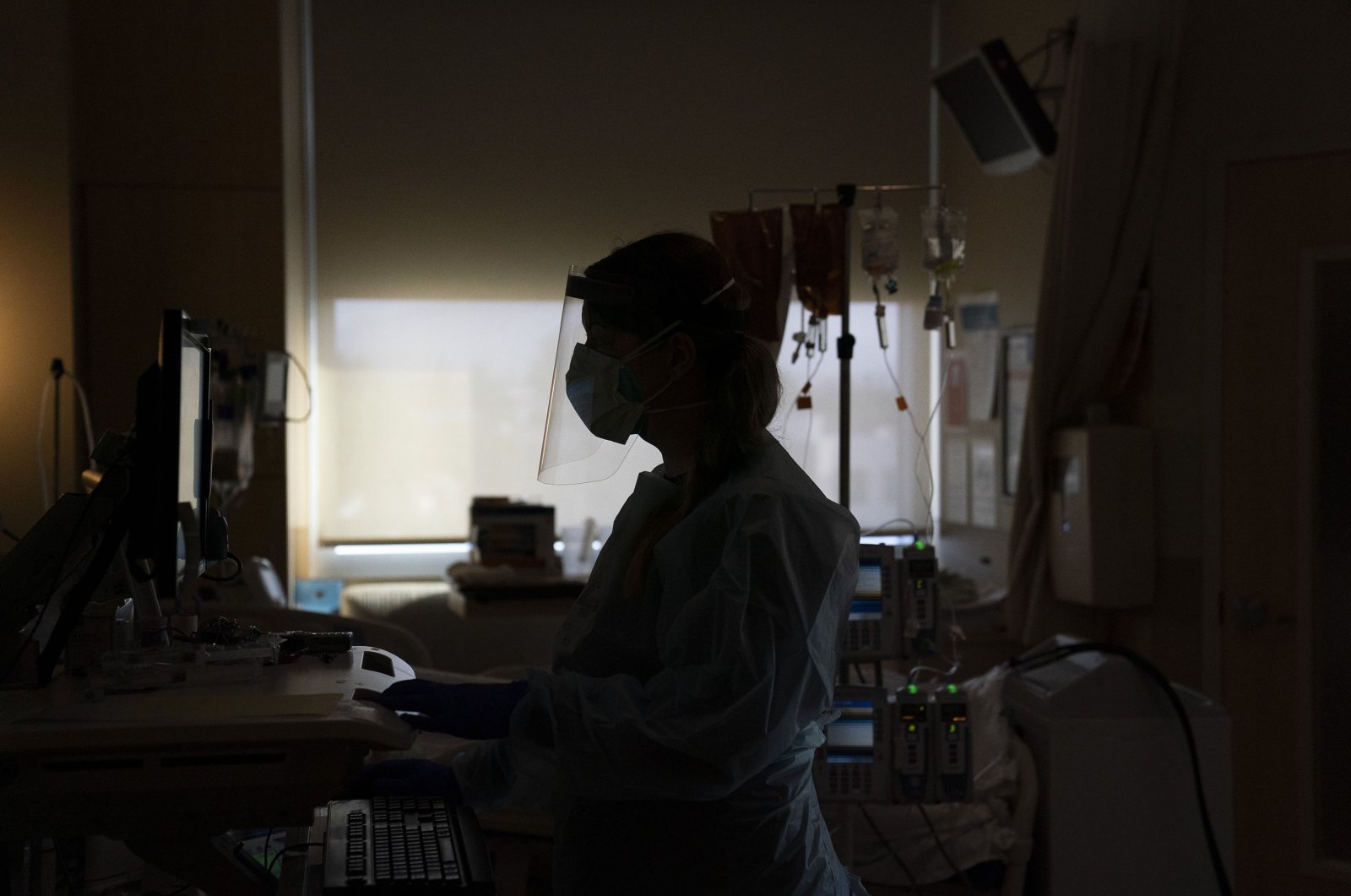Registered nurse Virginia Petersen works on a computer while assisting a COVID-19 patient at Providence Holy Cross Medical Center in the Mission Hills section of Los Angeles, Nov. 19, 2020. (AP Photo)