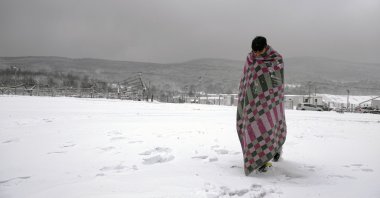A migrant walks through the snow wrapped in a blanket at the Lipa camp in northwestern Bosnia, near the border with Croatia, Dec. 26, 2020. (AP Photo)