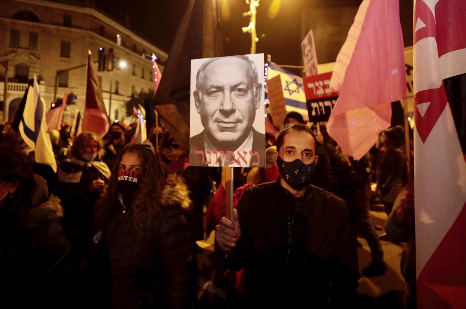 Israeli protesters hold signs during a demonstration against Israeli Prime Minister Benjamin Netanyahu in Jerusalem, Saturday, Dec. 26, 2020. (AP Photo)