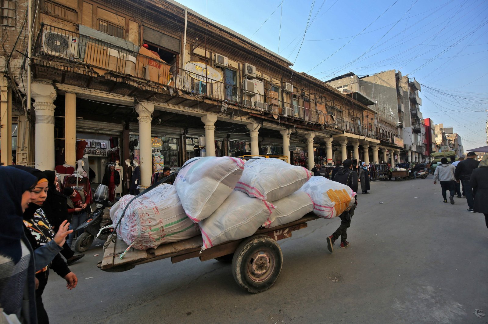 A man pulls a cart loaded with sacks near the Central Bank of Iraq's headquarters along Rashid Street in the center of Iraq's capital Baghdad, Dec. 22, 2020. (AFP Photo)