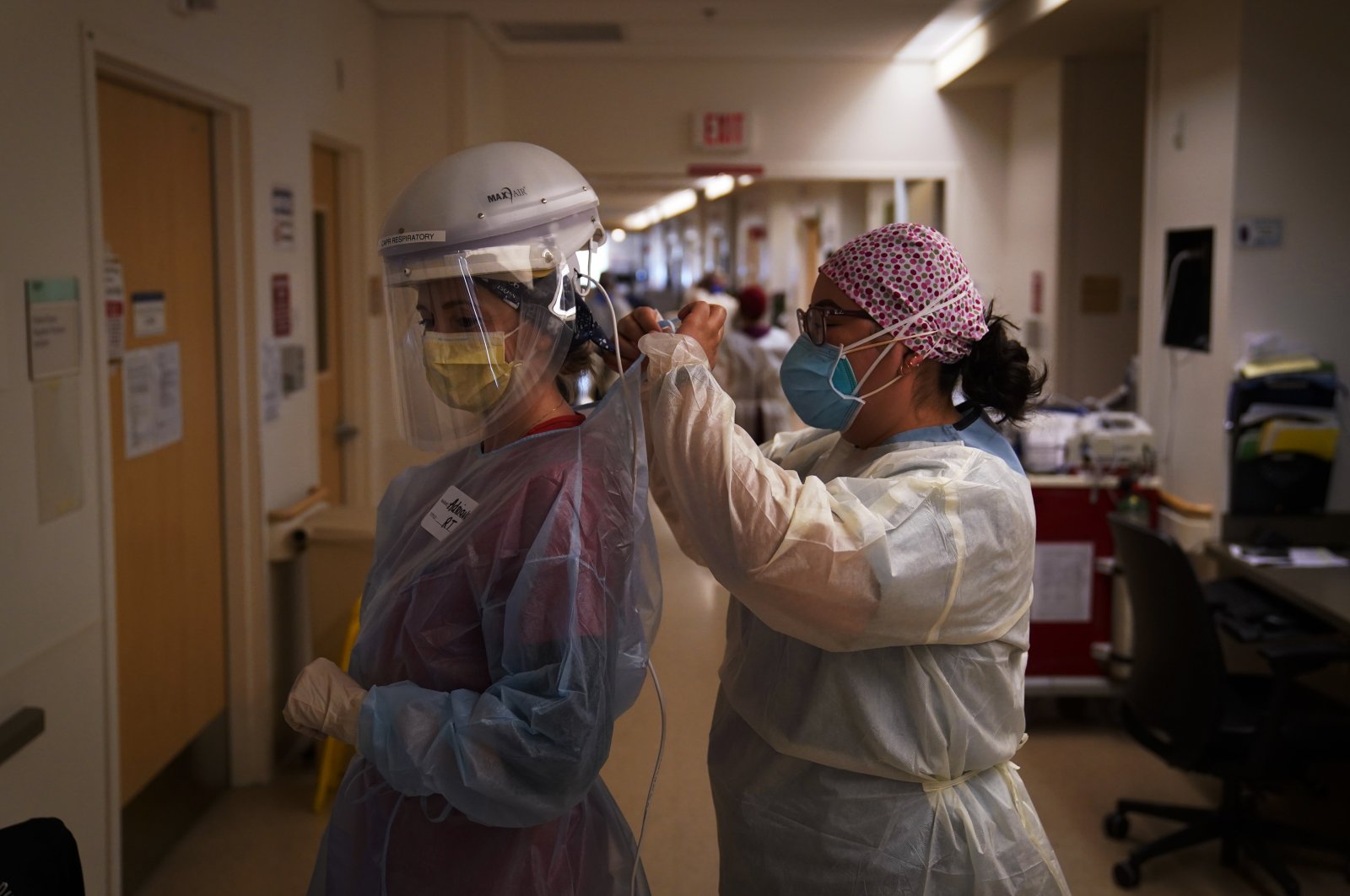 In this Dec. 22, 2020, file photo, registered nurse Dania Lima, right, helps fellow nurse Adriana Volynsky put on her personal protective equipment in a COVID-19 unit at Providence Holy Cross Medical Center in the Mission Hills section of Los Angeles, California. (AP Photo)