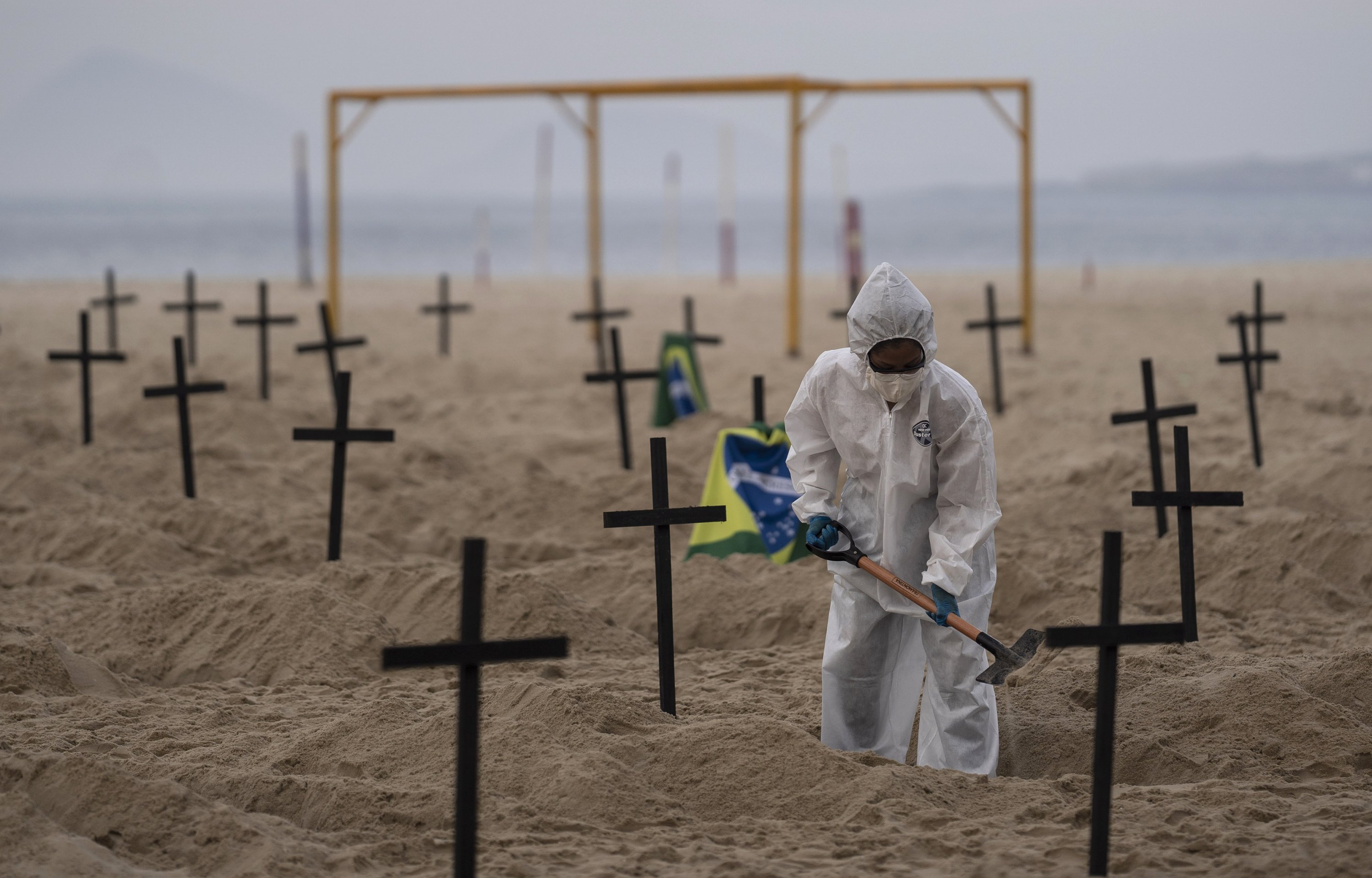 An activist digs symbolic graves on Copacabana beach, in front of a soccer goalpost, during a protest against the government
