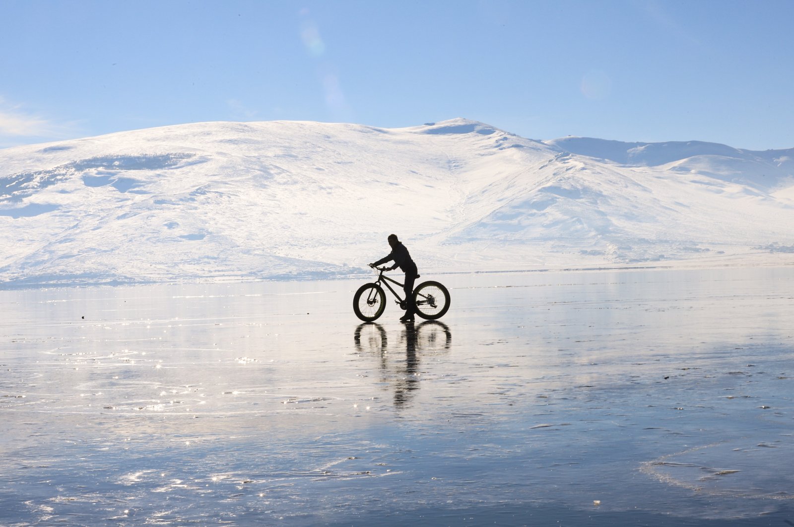 A man bikes across the frozen surface of Lake Çıldır in the Çıldır district of Ardahan province, eastern Turkey, Dec. 28, 2020. (IHA Photo)