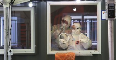 Medical workers in a booth work during COVID-19 testing at a makeshift clinic in Seoul, South Korea, Saturday, Jan. 2, 2021. (AP Photo)