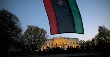 A Libyan holds up a Libyan flag while standing in front of the White House as then-President Barack Obama comments on U.S. involvement in Libya, Washington, D.C., March 28, 2011. (Getty Images)
