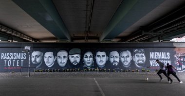 A boy and a man play football near graffiti depicting the nine victims of the Hanau shooting, under a bridge in Frankfurt am Main, Germany, June 20, 2020. (AP Photo)