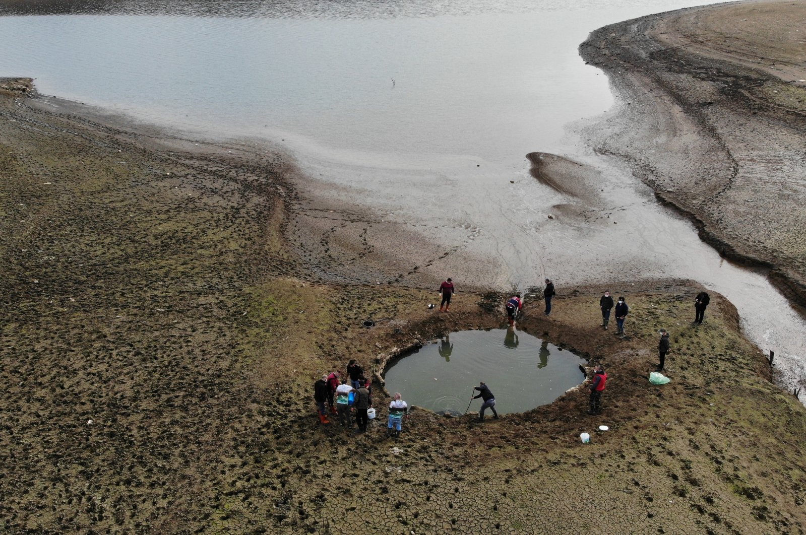 People work to rescue fish trapped in a pond in a dried-up part of Ömerli Dam, in Istanbul, Turkey, Jan. 4, 2021. (IHA Photo)