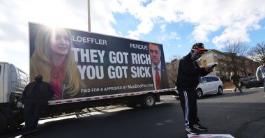 A man looks at his phone in front of a political ad at Georgia Democratic candidate Rev. Raphael Warnock Labor Canvass Launch at IBEW Local 613, Jan. 05, 2021, in Marietta, Georgia. (AFP Photo)