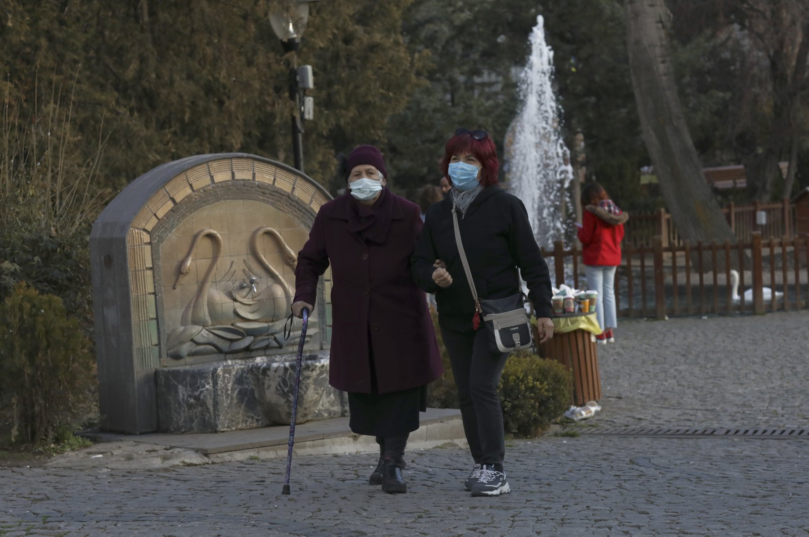 Women wearing face masks walk in a public garden in Ankara, Turkey, Jan. 1, 2021. (AP Photo)